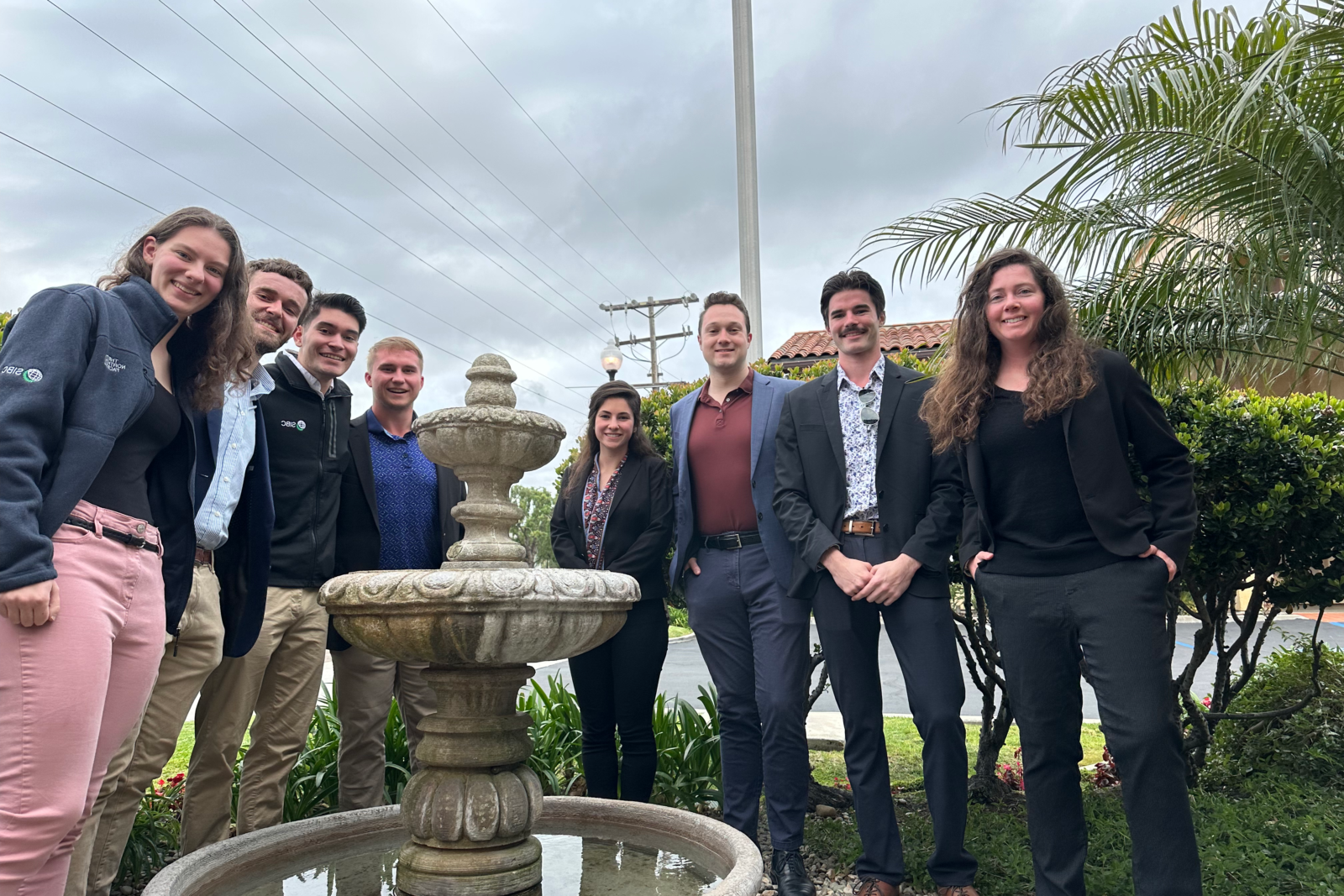 Students and professors in business casual outside with palm trees