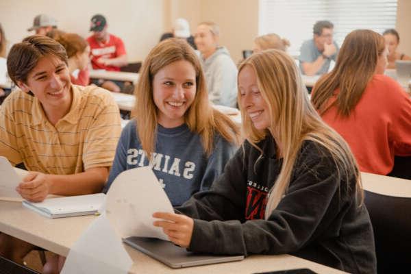 Students smiling looking at notes and assignment